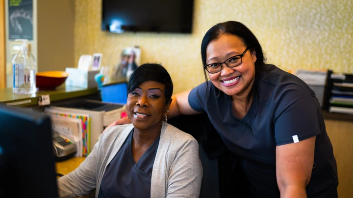 Hattie and Dr. Ona smiling at the Healthy Smile front desk